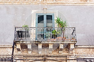 Balcony with flowerpots and house plants in a historic building in Catania, traditional architecture of Sicily, Italy