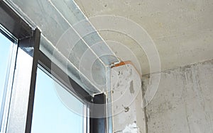 A balcony glass door, window is installed with a metal steel lintel, metal construction, panel above, connecting the ceiling and