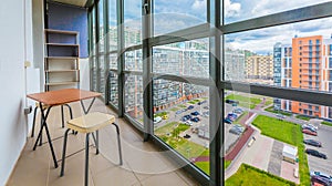 Balcony interior with chairs and table of modern apartment with a view on the courtyard.