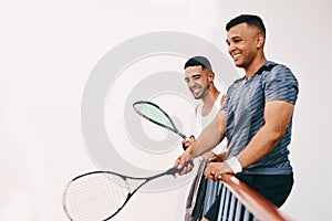 The balcony is reserved for squash fanatics. two young men watching a game of squash from the viewing gallery.