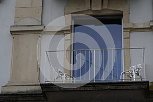 Balcony with two chairs. Low angle view on a balcony in a historical building with a modern French window.