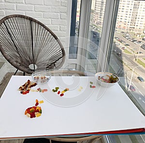 Balcony veranda. wicker chair, gray. against the background of a table with a white base. gummy bears on the table. panoramic