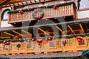 Balcony of Wooden Vintage Restaurant Building Decorated of Artificial Fir Tree with Lighting Garland and many Red Christmas Balls