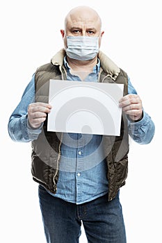 Bald adult man in a medical mask with a blank white sign in his hands. White background. Precautions during the coronavirus