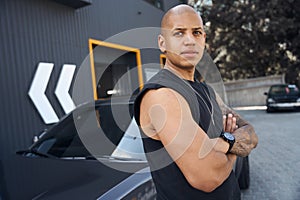 Bald African American man leaning on car standing outdoor