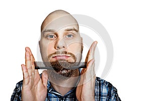 Bald bearded man with beard and comb in his hand combs against an isolated background