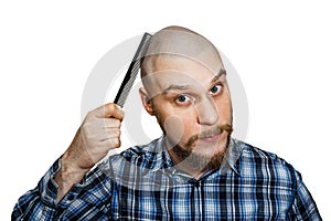 Bald bearded man with beard and comb in his hand combs against an isolated background