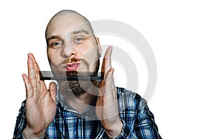 Bald bearded man with beard and comb in his hand combs against an isolated background