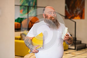 Bald bearded plump manstanding and holding a bottle with milk
