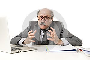 Bald business man 60s working stressed and frustrated at office computer laptop desk looking tired