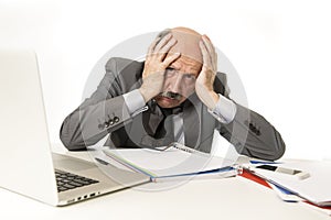 Bald business man 60s working stressed and frustrated at office computer laptop desk looking tired