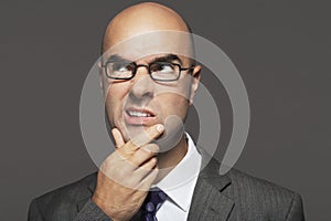 Bald Businessman With Hand On Chin Making Funny Face