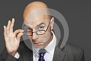 Bald Businessman With Hand On Glasses Making A Face