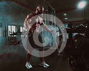 Bald Caucasian bodybuilder training chest using cable crossover in gym.