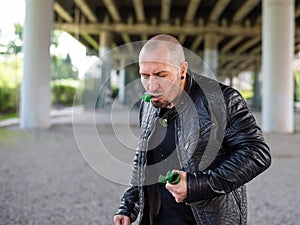 Bald Caucasian man eating broken glass. The bandit is eating a bottle of sugar. Joke or magic
