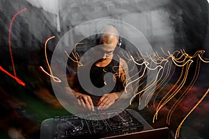 Bald club DJ with headphones mixes music