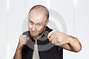 Bald evil guy criminal extortionist preparing for a fight and swinging his fist