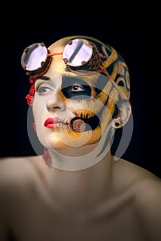Bald girl with a art make up and steampunk glasses