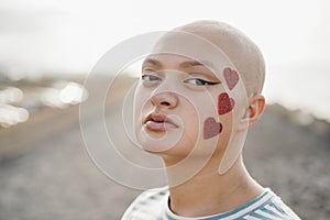 Bald girl wearing heart stickers with city on background - Main focus on right eye