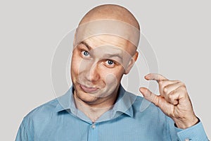 A bald guy shows a hand gesture meaning a very small amount of something