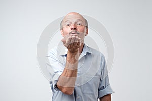 Bald handsome mature male blows air kiss, expresses his devotion and truthful love to his wife