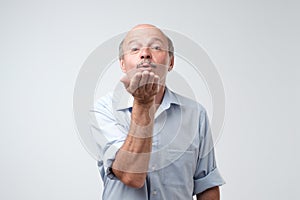 Bald handsome mature male blows air kiss, expresses his devotion and truthful love to his wife photo