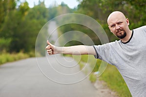 Bald-headed man hitching on road