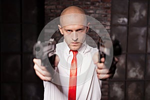 Bald hired killer in red tie aims a pistols