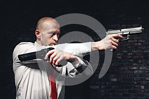 Bald hired killer in red tie aims a pistols