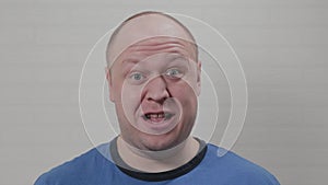 The bald man is angry with bulging eyes at the camera. Portrait of a bald man