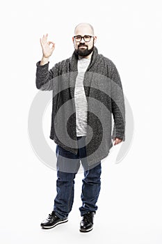 A bald man with a beard and glasses shows a sign of approx. Full height. White background. Vertical