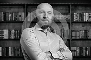 A bald man with a beard in the library.