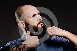 Bald man with a beard shortens his beard