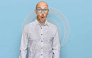 Bald man with beard wearing business shirt and glasses afraid and shocked with surprise expression, fear and excited face