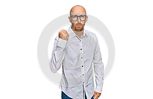 Bald man with beard wearing business shirt and glasses angry and mad raising fist frustrated and furious while shouting with anger