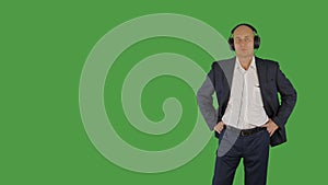 Bald man in business suit listening music in headphones on green background