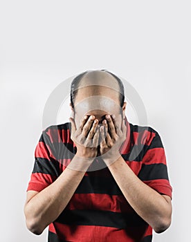 Bald man covering his face in shame in white background with space for text