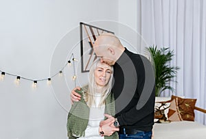 Bald man embracing and kissing his young blonde wife