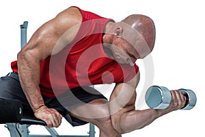 Bald man exercising with dumbbells while sitting on bench press