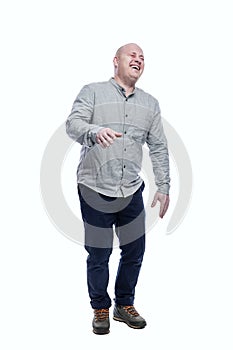 The bald man laughs contagiously. A guy in a gray shirt and dark blue jeans. Humor and positivity. Full height. Isolated on a