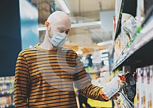 Bald man in medical face mask chooses products in supermarket, concept of coronavirus quarantine