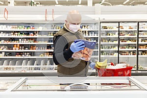 A bald man in a medical mask and gloves in a supermarket chooses products. Coronavirus pandemic