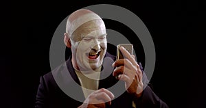 Bald man with painted face surfs internet laughing closeup