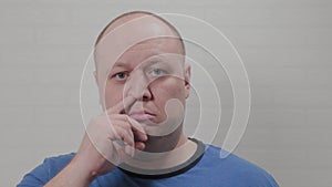 A bald man picks his nose at the camera. Portrait of a bald man.