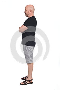 Bald man in profile with shirt shorts and sandals, arms crossed