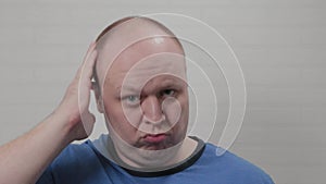 A bald man touches his bald head on camera. Portrait of a bald man.