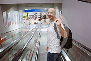 Bald man walking down the escalator with a backpack