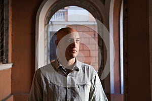 Bald middle-aged man smiling happy walking in the city against the background