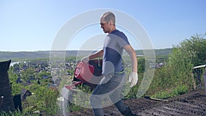 Bald mustachioed man joyfully watering the garden with red watering can