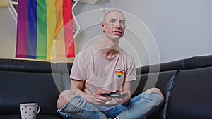 Bald queer man playing video games with a consol indoor